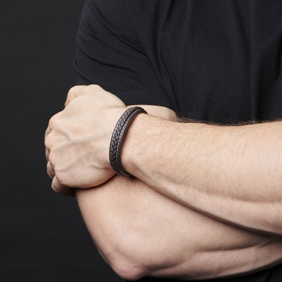 Close-up van een man met een donker gevlochten leren armband om zijn pols.