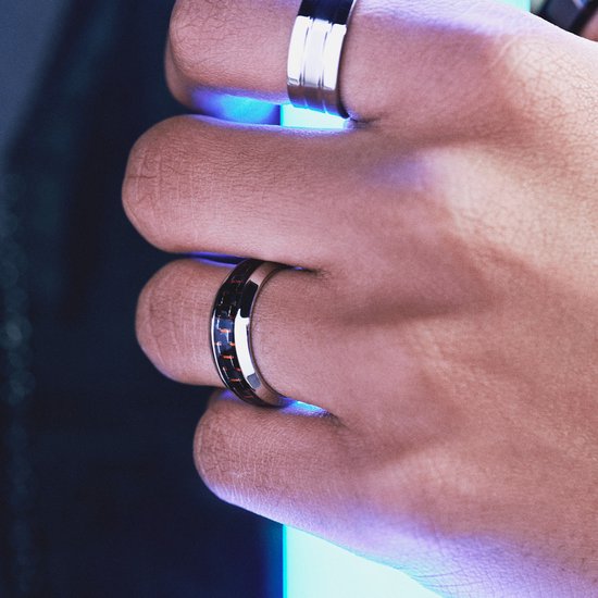 Close-up van een hand die een zilverkleurige ring met zwarte en rode koolstofvezelinleg draagt.