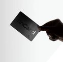 Hand met donkere huidskleur houdt zwarte InCard tracker met 'InCard' logo omhoog.