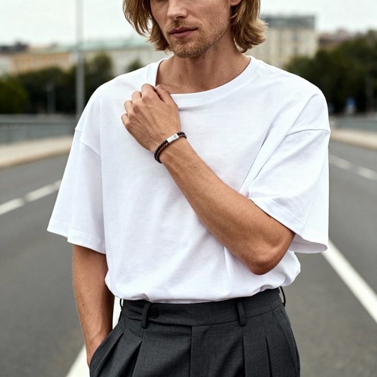 Model draagt een armband met zwarte en rode kralen en een gevlochten leren band met metalen sluiting.