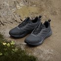 Paar zwarte Adidas Terrex trailrunningschoenen in de modder, met gras op de voorgrond.