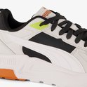 Close-up van een witte sneaker met zwarte mesh, witte Puma-streep en felgroene details.