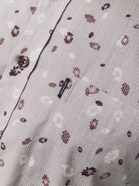 Close-up van de borstzak van een grijs overhemd met paarse en witte bloemenprint.