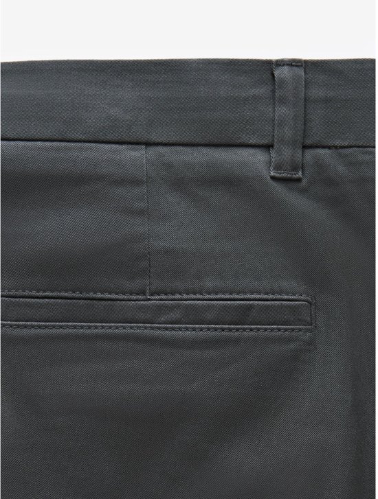 Detailopname van de achterzak van een grijze chinobroek.