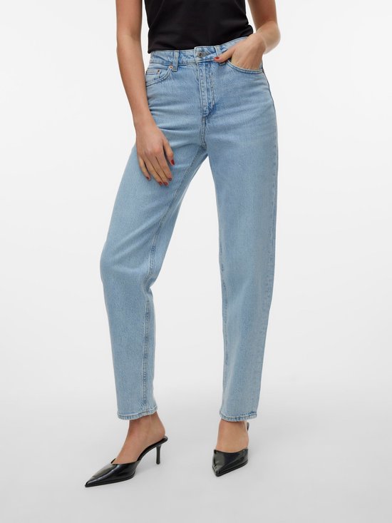 Model met de hand in de zak van een lichtblauwe jeans met een hoge taille en rechte pijpen. Draagt zwarte hakken.
