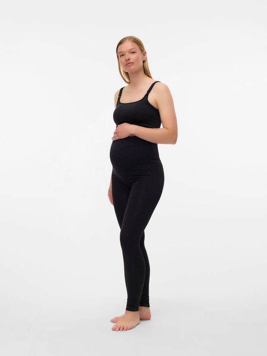 Zwanger model met blonde haren in een zwarte sportbeha en legging, hand op buik.