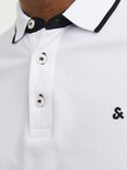 Detail van een wit poloshirt met zwarte kraagbies, knopen en logo.