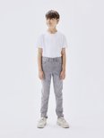 Jongetje in een witte T-shirt en strakke, grijze jeans.