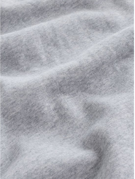 Close-up van de zachte grijze katoenen stof van de sweater met subtiele kreukels.