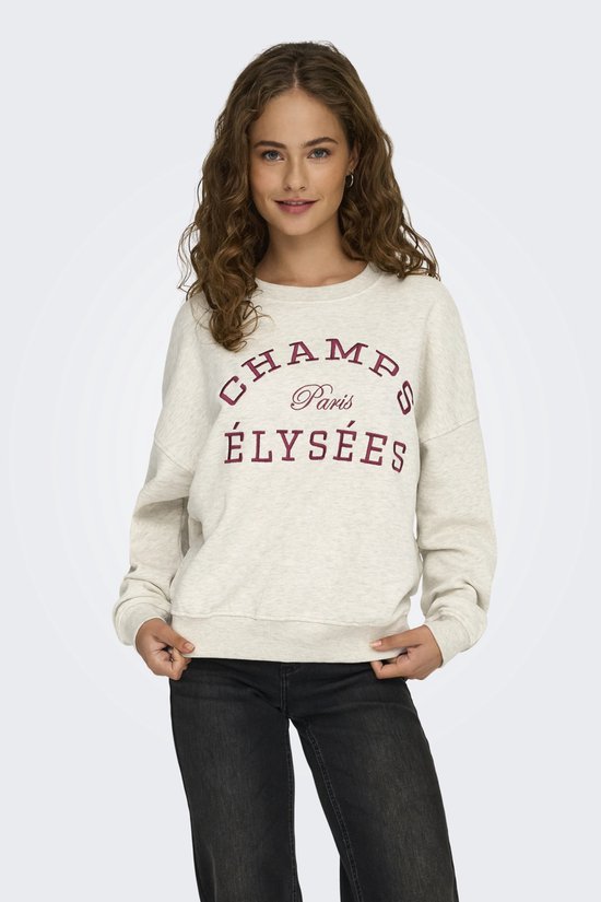 Model draagt een lichtgrijze sweater met 'CHAMPS Paris ÉLYSÉES' opdruk, gecombineerd met zwarte jeans.