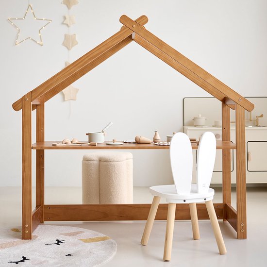 Houten huis bureau met een witte stoel met konijnenoren en speelgoedkeuken.