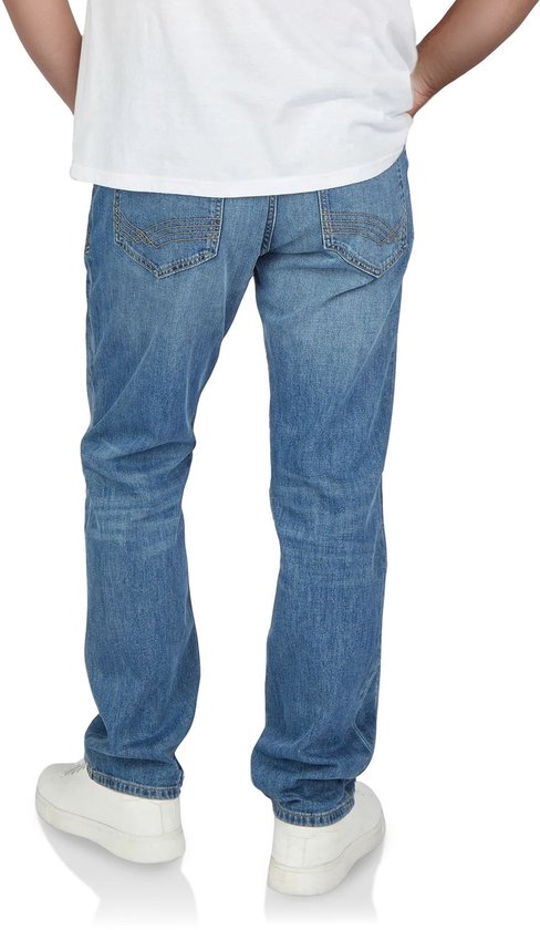 Achterkant van mannen in een lichtblauwe jeans met een witte top en witte sneakers. De broek heeft stiksels op de achterzakken.