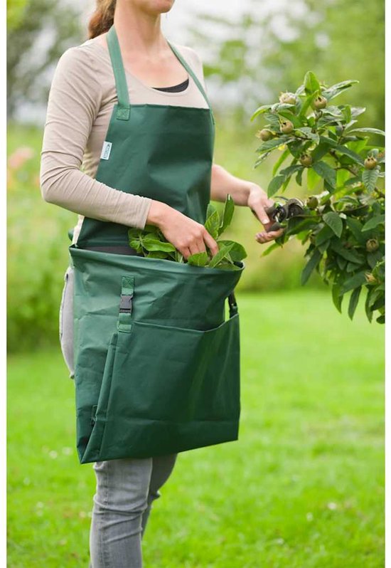 Vrouw met donkergroen tuig en opbergzak, knipt bladeren van een plant.