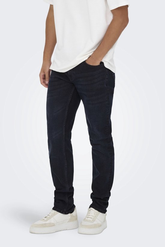 Zijaanzicht van een man in donkerblauwe jeans en wit T-shirt.