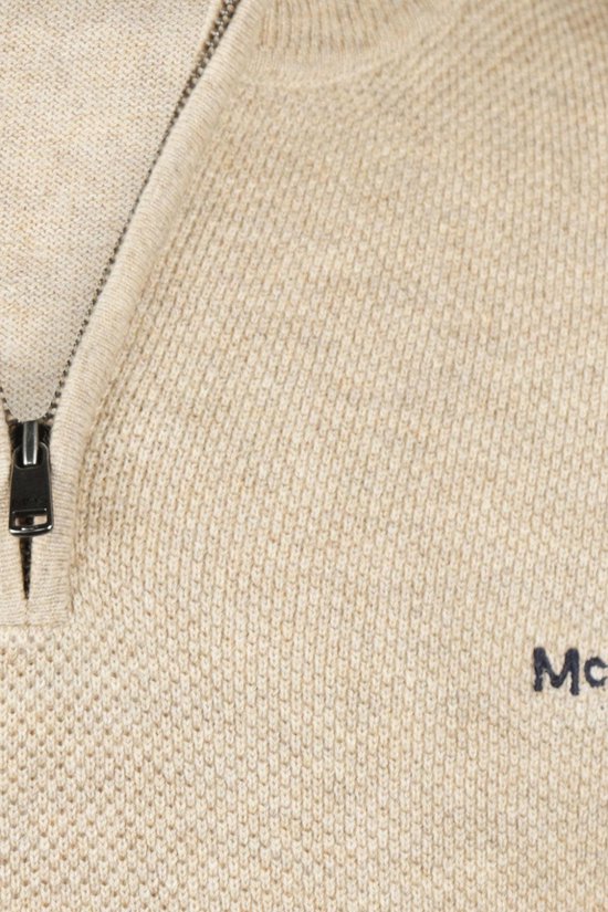 Detail van de beige trui met ritssluiting en geborduurd logo.