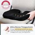 Een zwart orthopedisch zitkussen met gele lijnen, wordt op een stoel geplaatst en met de hand aangeraakt.