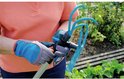 Persoon met grijze en blauwe tuinhandschoenen houdt een turquoise tuingereedschap met gebogen tanden vast.