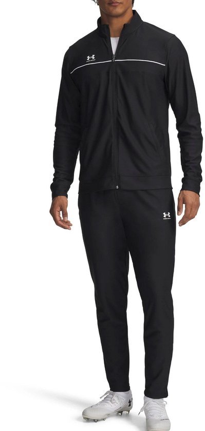 Man in zwart Under Armour trainingspak, jas met witte streep, broek met logo.