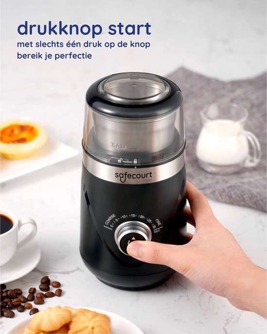 Hand drukt op de startknop van een zwarte Safecourt koffiemolen, met koffie en koekjes.