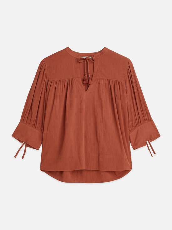 Blouse marron à col en V, détail de lacets avec pompons et manches bouffantes avec liens.