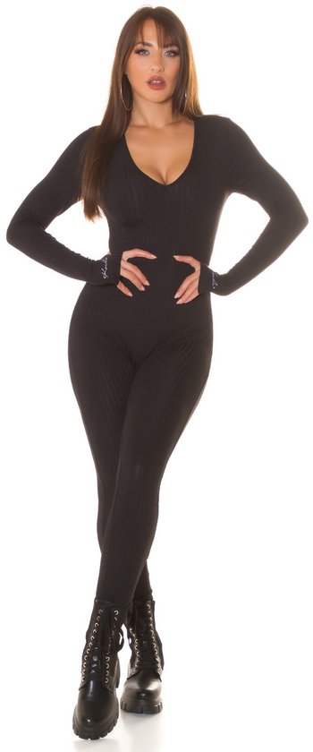 Model staat in zwarte Koucla jumpsuit met lange mouwen, V-hals en duimgaten. Ribgebreid.