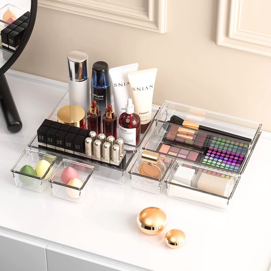 Transparante lade organizers gevuld met make-up en toiletartikelen.