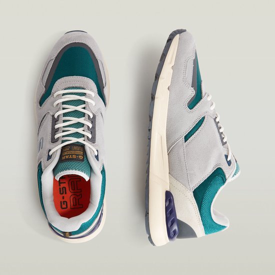 Lichtgrijze G-Star sneakers met teal-groene accenten. De sneakers hebben witte veters en een oranje binnenzool.
