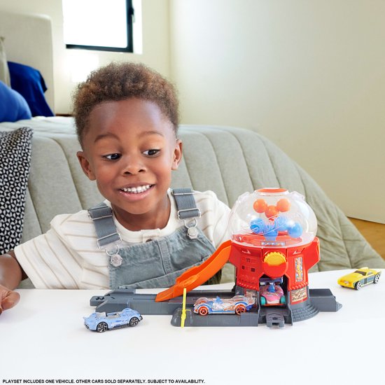Jongen speelt met rode Hot Wheels snoepautomaat speelset in slaapkamer