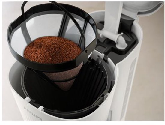 Vue intérieure d'une cafetière Philips blanche avec un panier-filtre noir rempli de café.