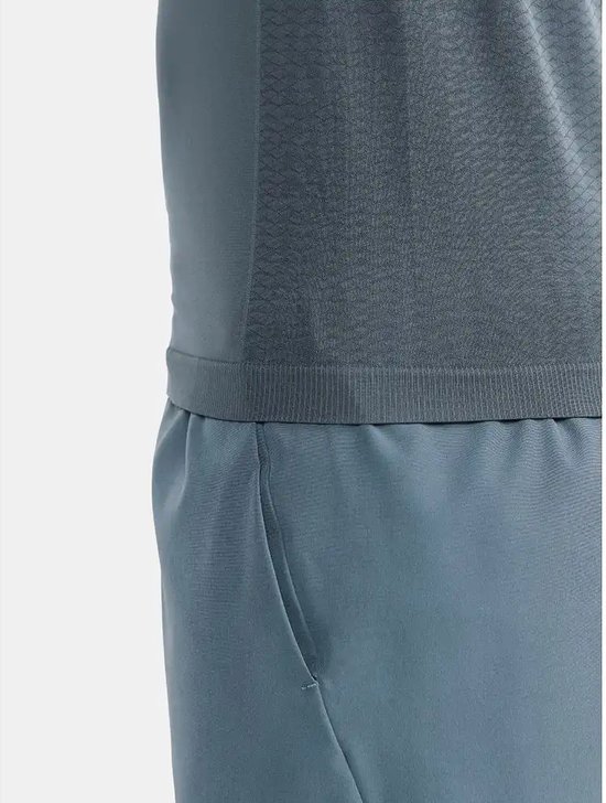 Gedetailleerde weergave van de tailleband van een blauwgrijze sportshort en de onderkant van een donkergrijs Craft sportshirt.