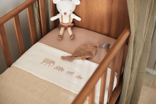 Wieg met gebreide deken met olifantenprint en een knuffelmuis.