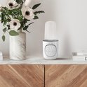 Witte Lionelo flesverwarmer met display, op een marmeren plank naast een vaas met bloemen.