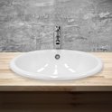 Lavabo ovale blanc avec robinet chromé sur un plan de travail en bois.