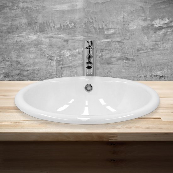 Lavabo ovale blanc avec robinet chromé sur un plan de travail en bois.