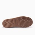 Onderkant van een bruine suède pantoffel met beige schapenvacht voering en gegroefde bruine zool.