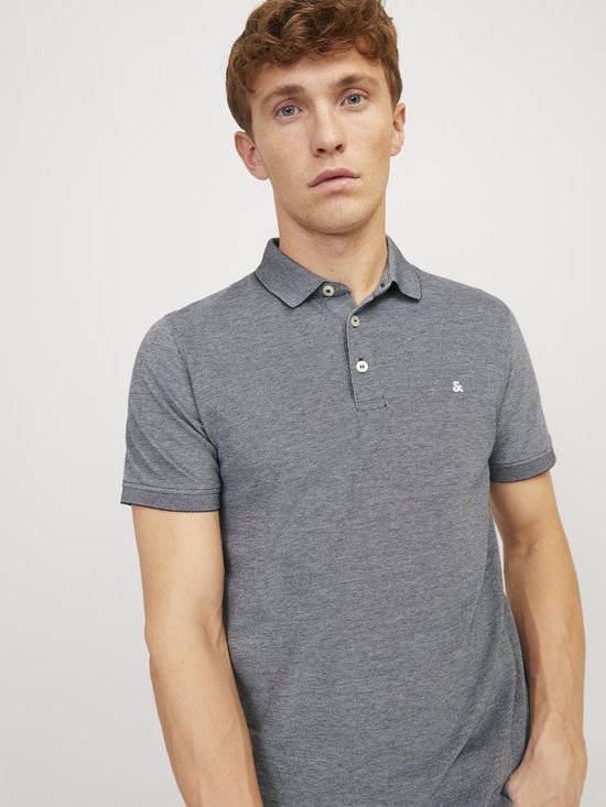 Man met kort, golvend blond haar draagt een grijs gemêleerd poloshirt met korte mouwen en Jack & Jones logo.