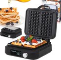 Zwarte wafelijzer met open deksel, bereidt twee wafels voor, met stapel wafels en fruit ernaast.