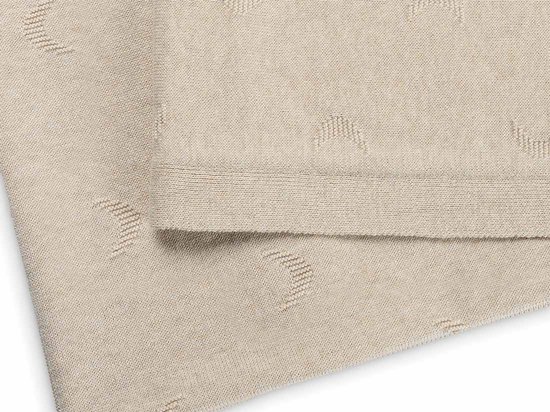 Close-up van een beige deken met een ingeweven patroon van maantjes.