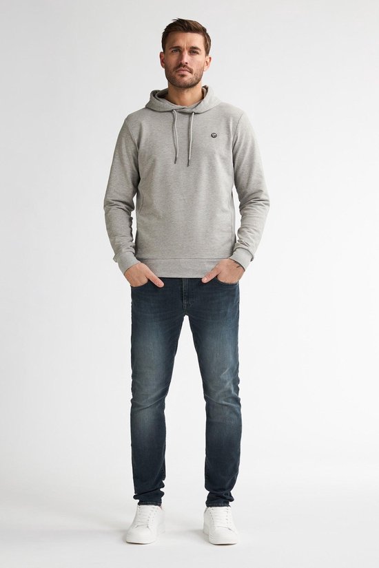 Man in grijze hoodie en donkerblauwe slim fit jeans, witte sneakers.