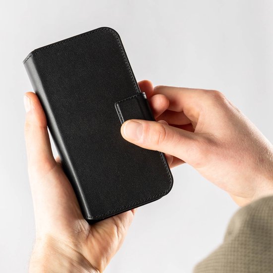 Handen die een zwarte lederen telefoonhoes sluiten.