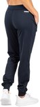 Vrouw in donkerblauwe sportbroek, achterkant met ritssluiting en sneakers.
