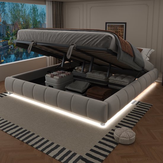 Beige gestoffeerd bed met hydraulische opbergruimte, open met witte LED-verlichting rondom. Beddengoed en kussens zijn opgeborgen.