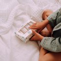 Kindje houdt een Naïf mini giftset vast op een wit, golvend textiel.