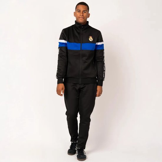 Model in zwart trainingspak met blauwe en witte strepen op de mouwen, Real Madrid logo op de borst.