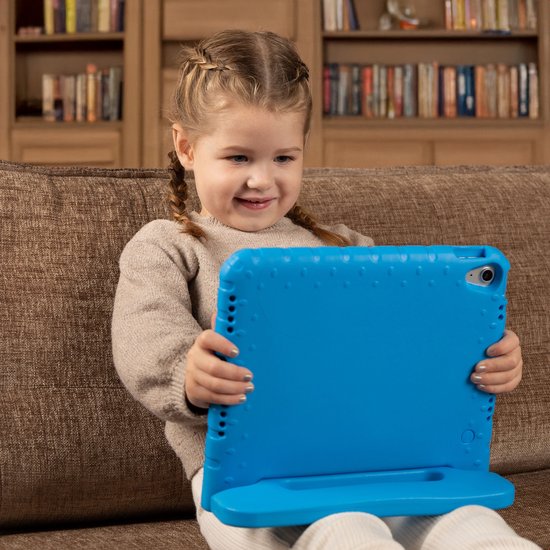 Een jong meisje met vlechten zit op een bank en gebruikt een blauw tablet in een hoes met standaard.