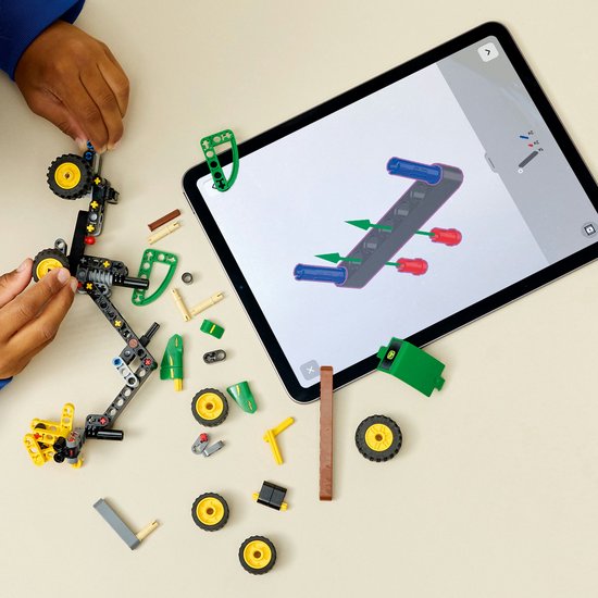 Kind bouwt LEGO Technic John Deere 1470H bosbouwmachine met behulp van een tablet.