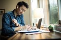 Man werkt aan bureau met witte Belkin oordopjes in, kijkt naar telefoon.