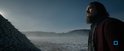 Leonardo DiCaprio met baard, in winterse kleding, kijkt uit over een besneeuwd landschap met mist.