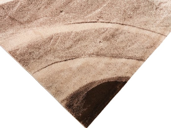 Close-up van een bruin en beige vloerkleed met golvende lijnen en een donkerbruine, ronde vorm aan de onderkant.