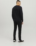 Een man staat met zijn rug naar de camera, gekleed in een zwarte trui en zwarte jeans.